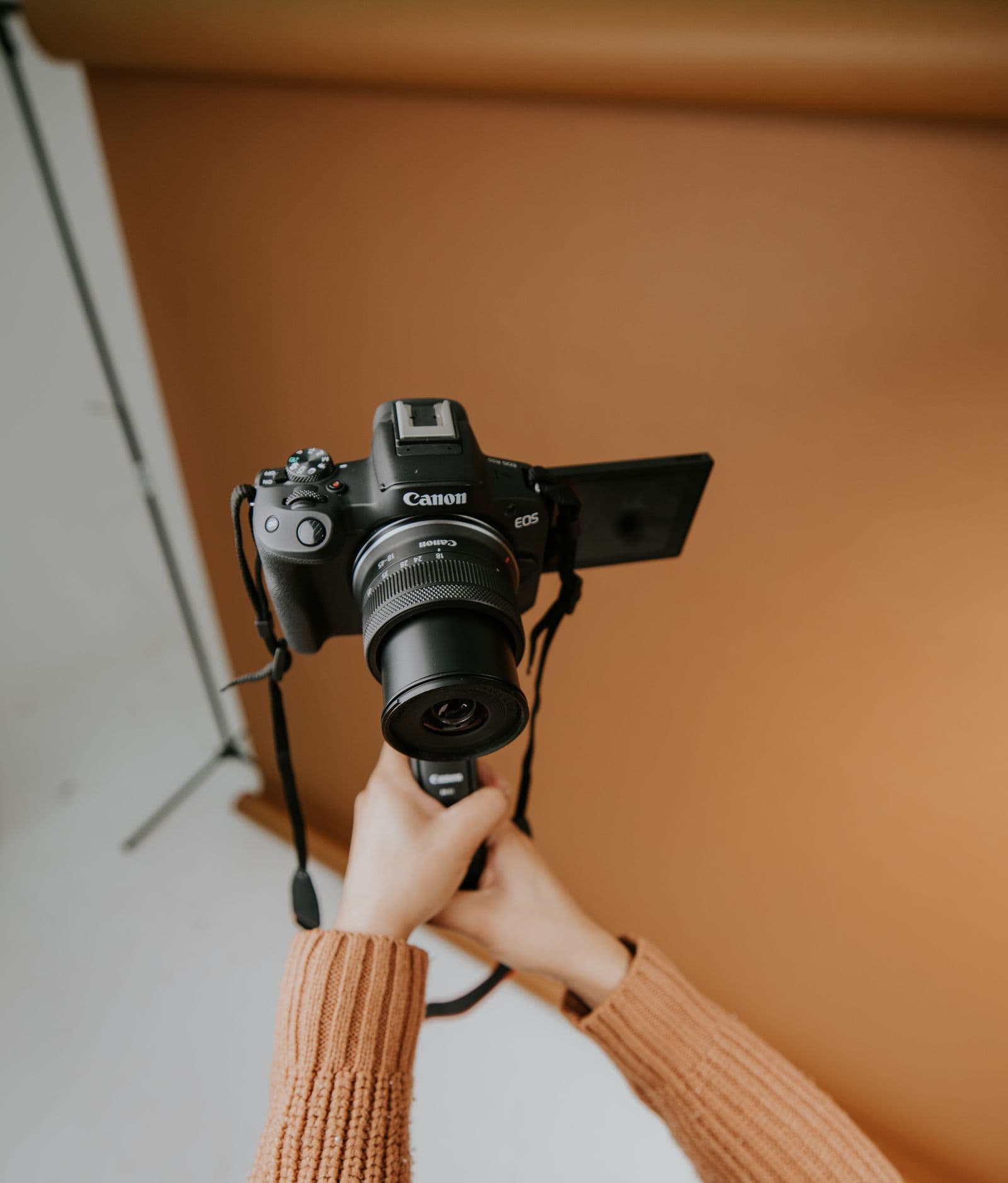 Hands holding a camera against an orange backdrop